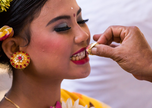 A Teenager Girl Having Her Teeth Blessed With A Ring By A Priest Before A Tooth Filing Ceremony