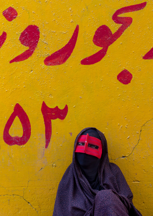 a bandari woman wearing the traditional mask called the burqa on a market, Hormozgan, Bandar Abbas, Iran