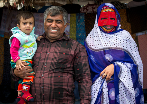a bandari woman with her husband and son wearing a traditional mask at panjshambe bazar, Hormozgan, Minab, Iran