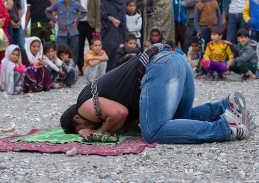 a strongman prays before struggling to break free of chains at the panjshambe bazar, Hormozgan, Minab, Iran