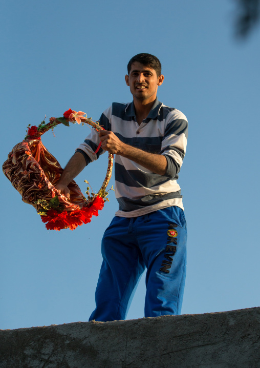 man throwing sweets from the house roof to the children during a wedding ceremony, Qeshm Island, Salakh, Iran