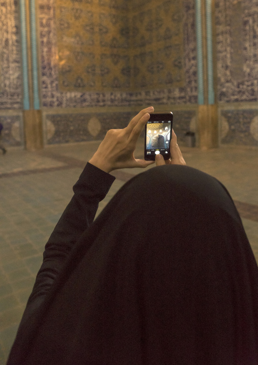 Iranian woman taking picture with her mobile phone inside sheikh lotfollah mosque, Isfahan province, Isfahan, Iran