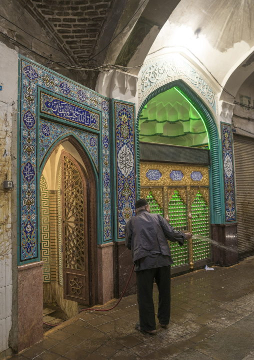 Man washing the facade of a mosque inside the bazaar, Isfahan province, Kashan, Iran