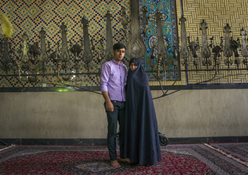 Mother and son inside the shrine of hasan ibn musa ibn ibn jafar in front of an alam, Isfahan province, Kashan, Iran