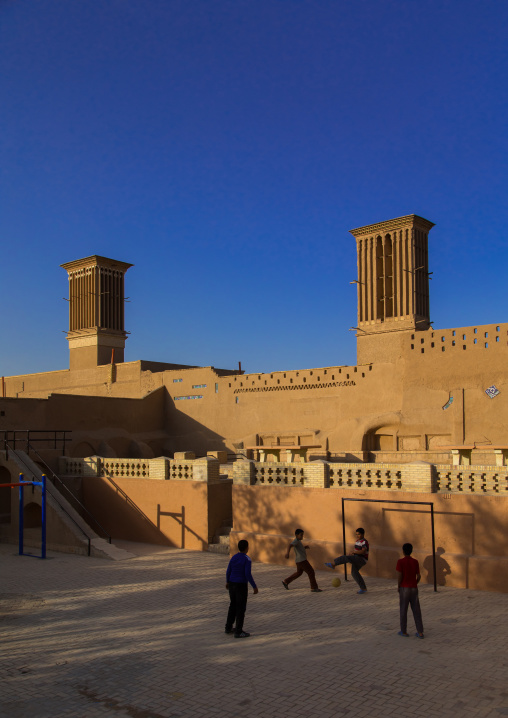 Children playing football in front of ind towers used as a natural cooling system in iranian traditional architecture, Yazd Province, Yazd, Iran