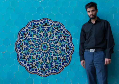 Iranian shiite man in Jameh mosque in front of a blue mosaic, Yazd Province, Yazd, Iran