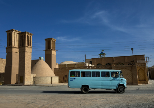 Bus in front of wind towers used as a natural cooling system for water reservoir in iranian traditional architecture, Isfahan Province, Nain, Iran