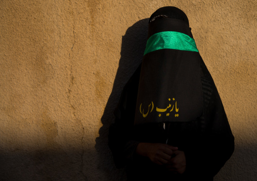 Portrait of an iranian shiite muslim woman with her face hidden by a veil mourning Imam Hussein on Tasua during the Chehel Manbar ceremony one day before Ashura, Lorestan Province, Khorramaba