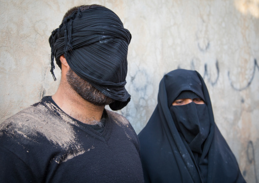 Portrait of iranian shiite muslim couple with their faces hidden by a veil mourning Imam Hussein on Tasua during the Chehel Manbar ceremony one day before Ashura, Lorestan Province, Khorramab