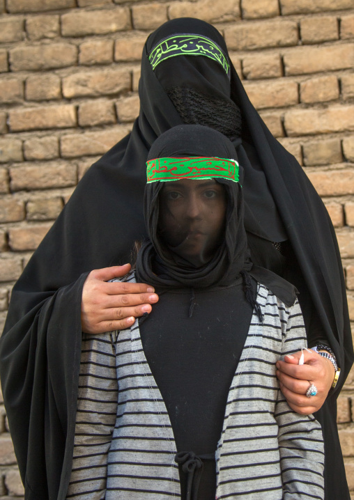 Portrait of an iranian shiite muslim mother and son with their faces hidden by a veil mourning Imam Hussein on Tasua during the Chehel Manbar ceremony one day before Ashura, Lorestan Province