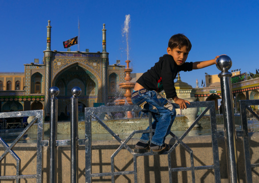 Boy jumping a fence in Fatima al-Masumeh shrine, Central County, Qom, Iran
