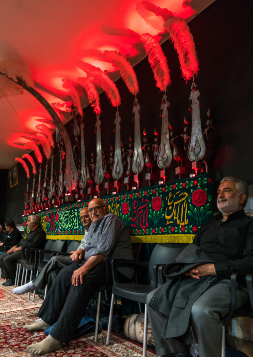 Shiite men standing under an Alam in a Hosseinieh decorated for Muharram, Isfahan Province, Kashan, Iran