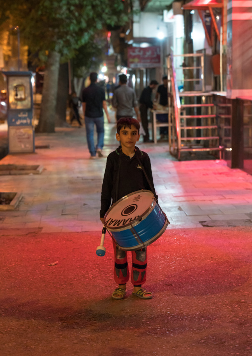 A child plays drums at night in the street during Muharram, Lorestan Province, Khorramabad, Iran