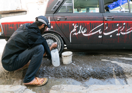 A shiite iramian man washes his car decorated for Ashura celebrations to commemorate the martyrdom anniversary of Hussein, Lorestan Province, Khorramabad, Iran