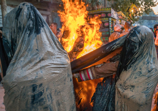 Iranian shiite muslim women gather around a bonfire after rubbing mud on their chadors during the Kharrah Mali ritual to mark the Ashura day, Lorestan Province, Khorramabad, Iran