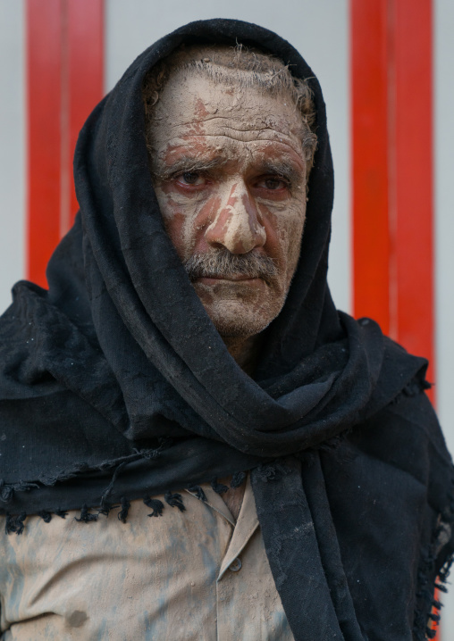 Portrait of an iranian shiite muslim man with mud stains during the Ashura day, Lorestan Province, Khorramabad, Iran