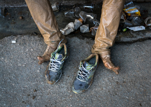 Iranian shiite muslim man legs and shoes after rubbing mud on his clothes during the Kharrah Mali ritual to mark the Ashura ceremony, Lorestan Province, Khorramabad, Iran