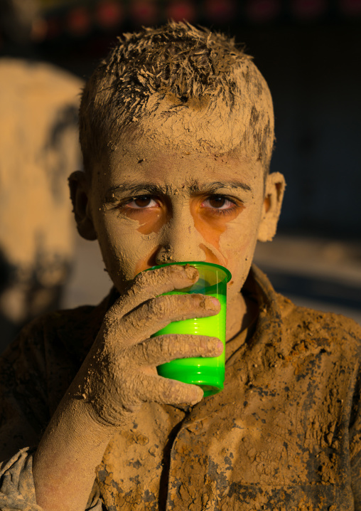 Iranian shiite muslim boy drinks milk after rubbing mud on his body early in the morning of Ashura day, Lorestan Province, Khorramabad, Iran
