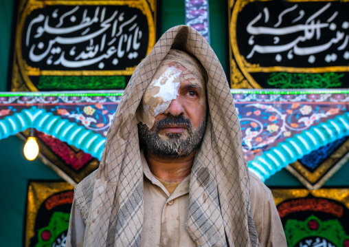 Iranian shiite muslim man with a wounded eye after rubbing mud on his clothes during the Kharrah Mali ritual to mark the Ashura ceremony, Lorestan Province, Khorramabad, Iran