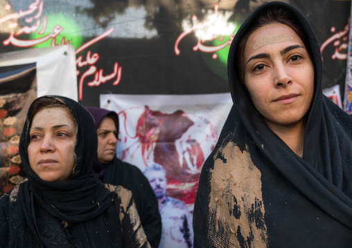 Iranian shiite muslim women with mud stains watch the rubbing mud ritual during the Ashura ceremony, Lorestan Province, Khorramabad, Iran