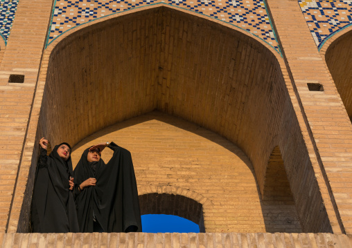 Two young veiled women on Khaju bridge Pol-e Khaju looking away, Isfahan Province, Isfahan, Iran