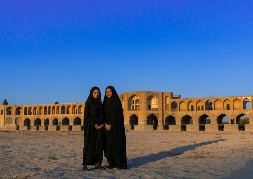 Portrait of two young women in chadors in front of Khaju bridge Pol-e Khaju, Isfahan Province, Isfahan, Iran