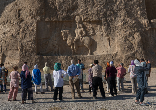 Tourists looking at the triumph relief of Shapur i at Naqsh-e Rustam necropolis, Fars Province, Shiraz, Iran