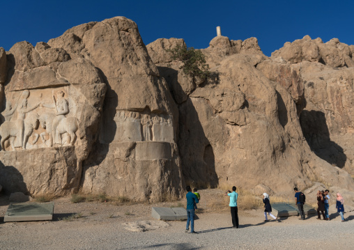 Tourists visiting the achaemenian royal tombs in Naqsh-e Rustam necropolis, Fars Province, Shiraz, Iran