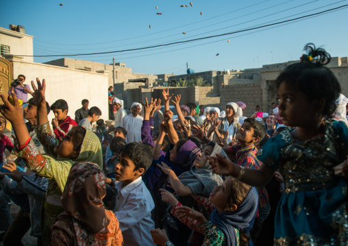 children catching sweets thrown from the house roof during a wedding ceremony, Qeshm Island, Salakh, Iran