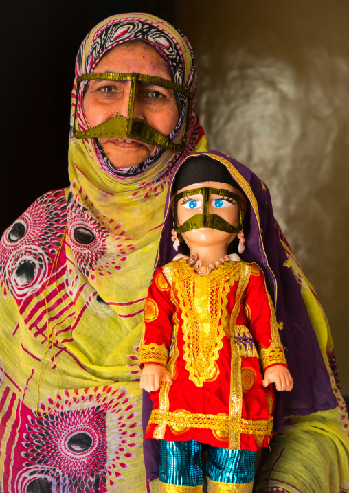 a bandari woman wearing a traditional mask called the burqa with a decorated doll for nowruz festival, Qeshm Island, Salakh, Iran