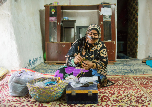 a bandari woman with a traditional mask called the burqa sewing, Qeshm Island, Salakh, Iran