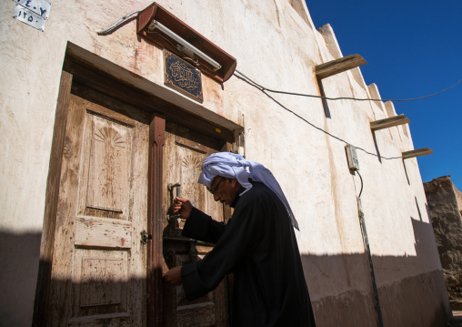 man opening the wooden door of an old house, Hormozgan, Bandar-e Kong, Iran