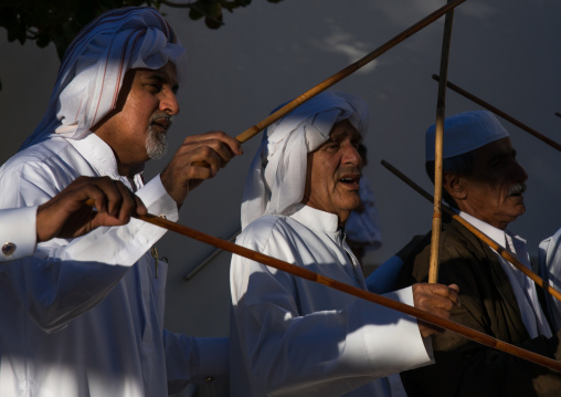 men dressed in white dancing with sticks during a wedding ceremony, Hormozgan, Bandar-e Kong, Iran