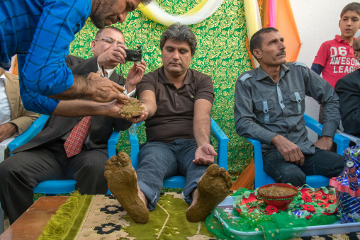 groom hands and feet being covered with henna during his wedding ceremony, Hormozgan, Kushkenar, Iran