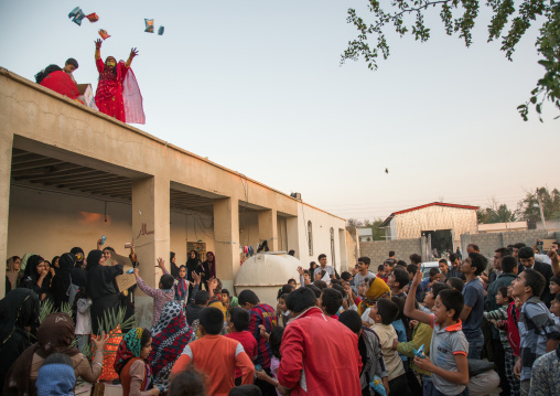 women with face masks throwing sweets to kids during a wedding, Hormozgan, Kushkenar, Iran