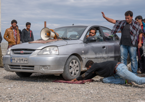 car rolling on the hand of a man during a show on a market, Hormozgan, Minab, Iran