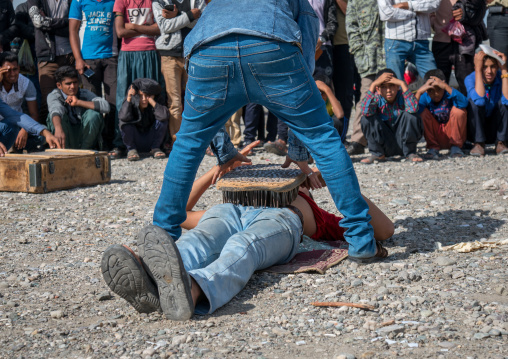 a nail bed lying on a man belly during a show on a market, Hormozgan, Minab, Iran
