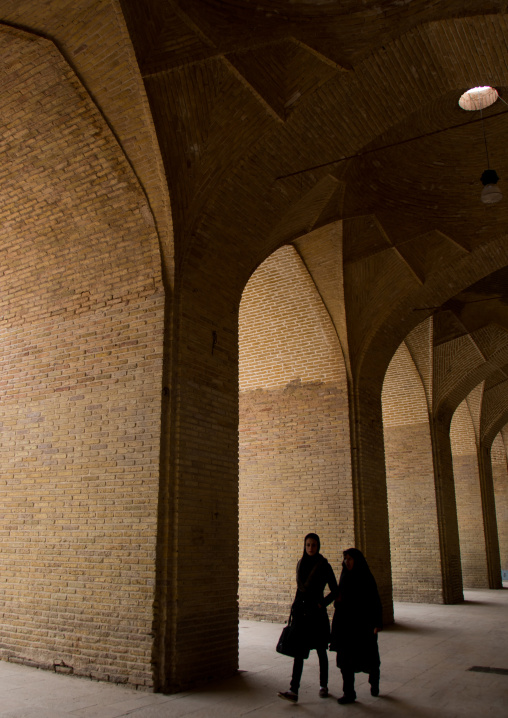 women passing under the arches of ganjali khan square, Central County, Kerman, Iran