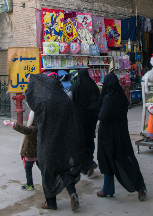 women passing in front bugs bunny and bob the sponge towels in bazaar on ganjali khan square, Central County, Kerman, Iran