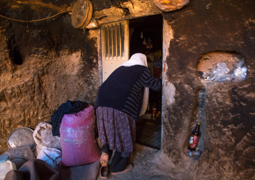 old widow woman entering her troglodyte house, Kerman province, Meymand, Iran