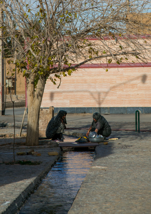 women washing clothes in a water channel, Ardakan County, Aqda, Iran