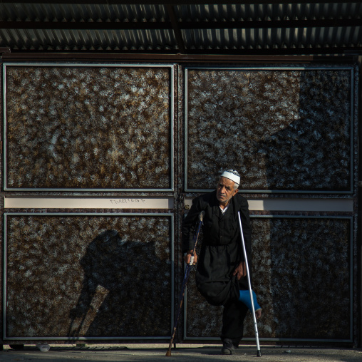 Elderly Man With Crutches In Front Of A Door During Ashura Celebration, The Day Of The Death Of Imam Hussein, Kurdistan Province, Bijar, Iran