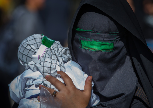 Iranian Shiite Muslim Woman Holding Her Baby Mourning Imam Hussein On The Day Of Tasua With Her Face Covered By A Veil, Lorestan Province, Khorramabad, Iran