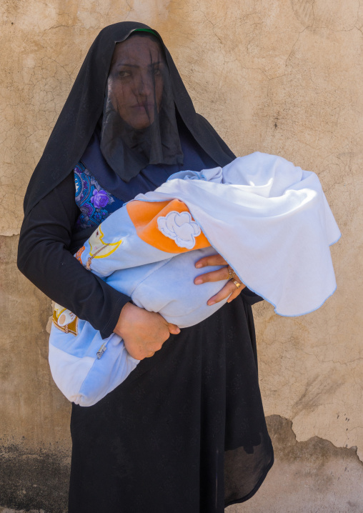 Iranian Shiite Muslim Woman Holding Her Baby Mourning Imam Hussein On The Day Of Tasua With Her Face Covered By A Veil, Lorestan Province, Khorramabad, Iran
