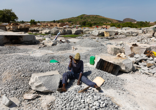 African woman crashing stones in a granite quarry, Savanes district, Shienlow, Ivory Coast