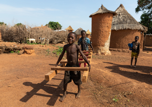 African children carrying a ladder in front of granaries, Savanes district, Niofoin, Ivory Coast