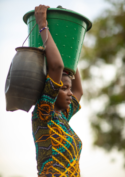 Portrait of a Peul tribe girl carrying a bucket full of water on the head, Savanes district, Boundiali, Ivory Coast
