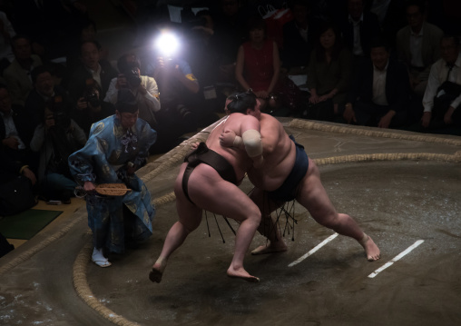 Two sumo wrestlers fighting at the ryogoku kokugikan arena, Kanto region, Tokyo, Japan
