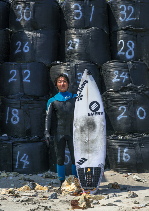 Japanese surfer in front of bags with contaminated sand after the daiichi nuclear power plant irradiation, Fukushima prefecture, Tairatoyoma beach, Japan
