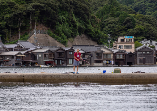 Japanese man fishing in front of funaya houses, Kyoto prefecture, Ine, Japan